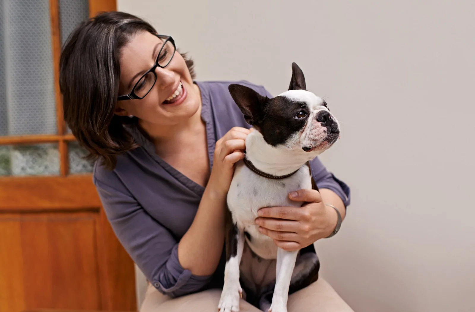 Boston terrier cinsi köpeğiyle gülümseyen kadın